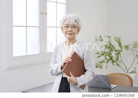 Elderly businesswoman standing in the office Elderly businesswoman standing in the office 119693300