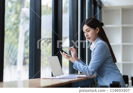 Beautiful Young Accountant Working in Modern Workspace with Laptop and Smartphone, Professional Businesswoman in Office Environment, Focused on Financial Tasks, Productivity and Efficiency Beautiful Young Accountant Working in Modern Workspace with Laptop and Smartphone, Professional Businesswoman in Office Environment, Focused on Financial Tasks, Productivity and Efficiency 119693807