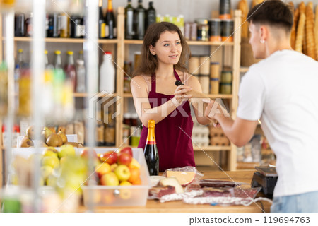 Young woman seller offers wine to man Young woman seller offers wine to man 119694763