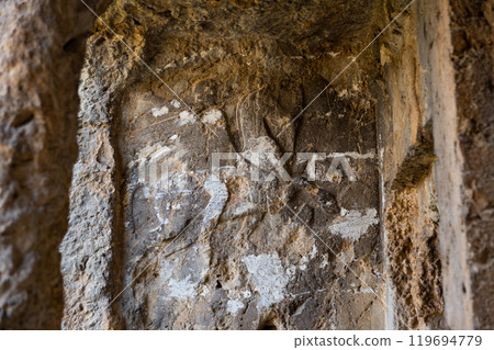 Carved stone reliefs in cliff near ancient rock tombs in Tlos, Turkey 119694779