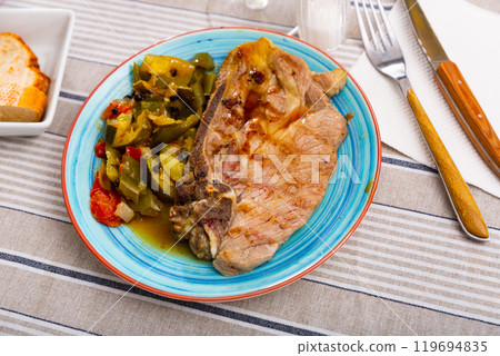 Juicy roast pork on a plate with stewed vegetables 119694835