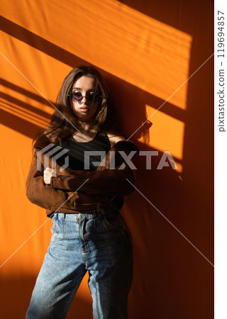 Portrait of a beautiful fashionable woman on an orange brown background 119694857