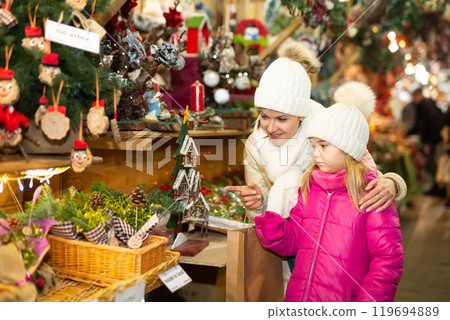 Young girl and her mother are buying Christmas ornamentals in the market outdoor 119694889