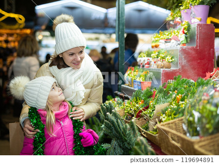 Happy mom with daughter buy spruce twigs for Christmas celebration Happy mom with daughter buy spruce twigs for Christmas celebration 119694891