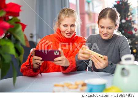 Woman and her daughter playing on smartphones 119694932