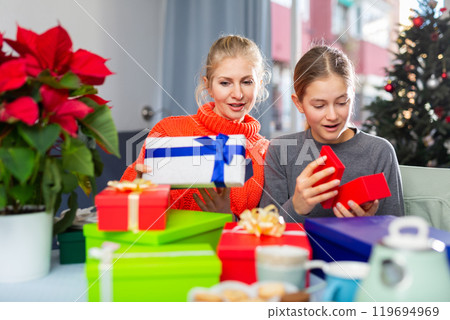 Woman and her daughter opens Christmas gift boxes 119694969