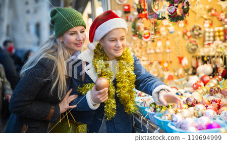 Girl and her mother purchasing decorations at christmas market 119694999