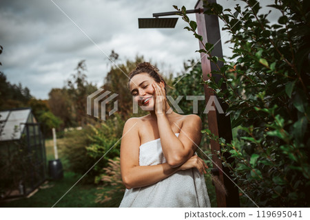Beautiful woman resting in garden after using home sauna. Woman taking care of her body and mind, wellness routine. Beautiful woman resting in garden after using home sauna. Woman taking care of her body and mind, wellness routine. 119695041