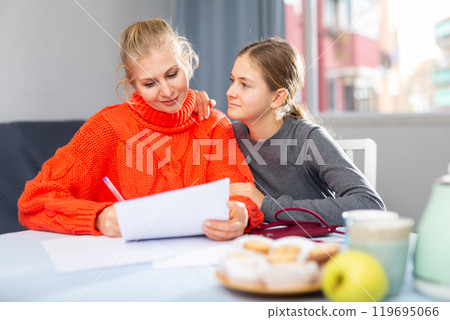 Mother and daughter reading letter 119695066