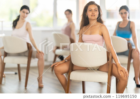 Female dancers wearing high heels shoes stretching legs while practicing in studio before dance performance providing Female dancers wearing high heels shoes stretching legs while practicing in studio before dance performance providing 119695150