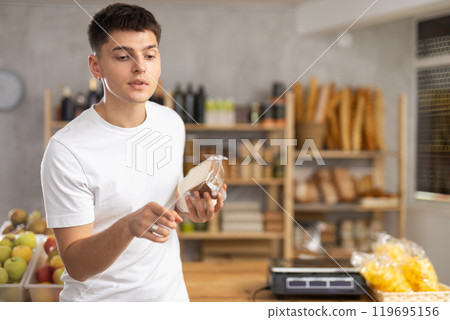 Young guy is choosing cheese in grocery store Young guy is choosing cheese in grocery store 119695156