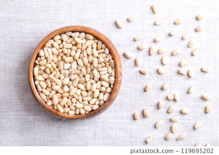 Pine nuts in a wooden bowl on linen fabric. Also known as pinon, pinoli, or pignoli. Shelled seeds and fruits of Korean pines, Pinus koraiensis. Used for pesto, added to dishes or baked into bread. Pine nuts in a wooden bowl on linen fabric. Also known as pinon, pinoli, or pignoli. Shelled seeds and fruits of Korean pines, Pinus koraiensis. Used for pesto, added to dishes or baked into bread. 119695202