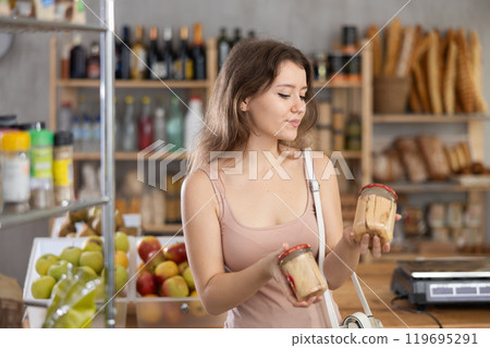 Young girl is choosing canned food in grocery store 119695291