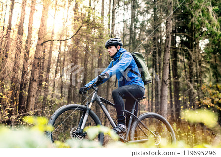 Active man on bike in the middle of beautiful forest, early autumn morning. Concept of healthy lifestyle. Low angle view. 119695296