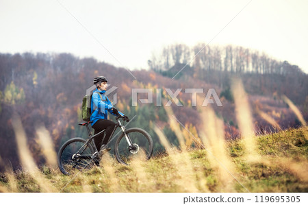 Active man on bike in the middle of autumn nature, resting and enjoying beautiful view. Concept of active and healthy lifestyle Active man on bike in the middle of autumn nature, resting and enjoying beautiful view. Concept of active and healthy lifestyle 119695305