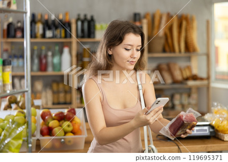 Young girl is scanning QR on dried meat in grocery store Young girl is scanning QR on dried meat in grocery store 119695371
