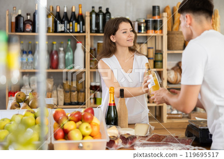 Female shop assistant helping customer select bottle of wine Female shop assistant helping customer select bottle of wine 119695517