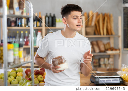 Young guy is choosing cheese in grocery store 119695543