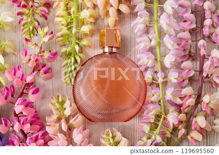 round brown cosmetic perfume bottle and lupine flowers on wooden background. Mockup, spring summer flat lay. glass perfume bottle for branding and label 119695560