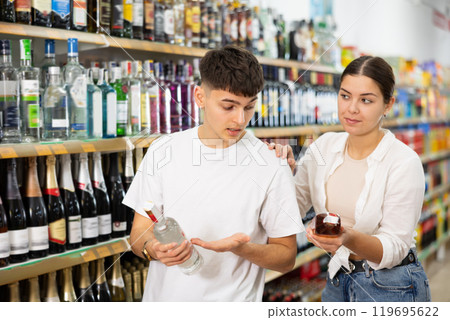 Young couple looking to buy nice bottle of liquor in supermarket Young couple looking to buy nice bottle of liquor in supermarket 119695622