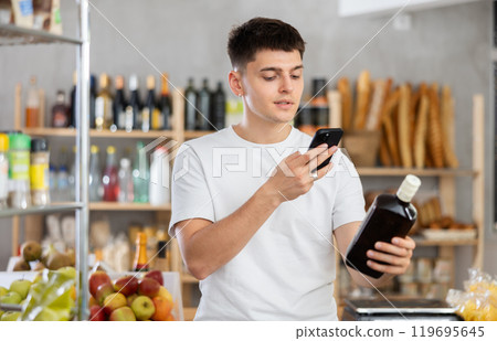 Young guy is scanning QR on whiskey in grocery store 119695645