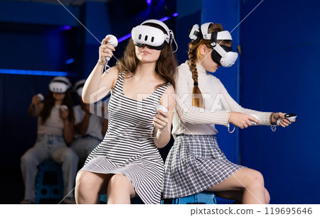 Girl in headset playing VR games against each other in room 119695646