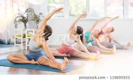 Young girl stretching in Parivrtta Janu Sirsasana in yoga studio 119695933