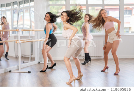 Girls in heels learn to move to beat of music and combine rhythm and smooth movements 119695936