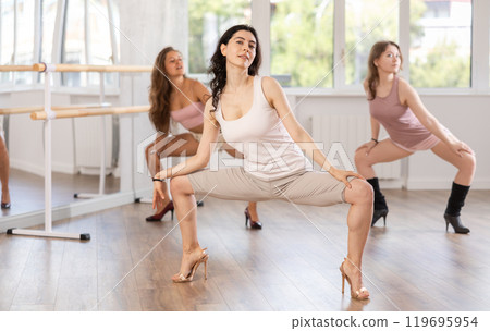 Girls in heels learn to move to beat of music and combine rhythm and smooth movements 119695954
