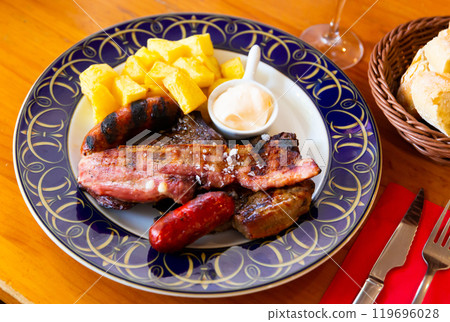 Grilled sausages and pork with potatoes and sauce 119696028