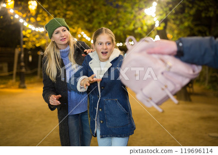 Street thief stealing backpack of scared teenage girl walking with mother 119696114