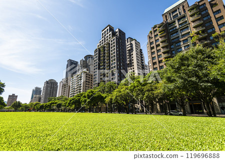 Low-angle view of green park space and modern buildings on both sides in downtown Taichung, Taiwan, It is near the National Taichung Theater. 119696888