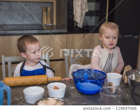 Two children joyfully making cookies in a warm kitchen, developing culinary abilities and connecting through a family tradition concept of cooking food from dough,cook at home 119697006