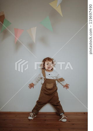 Portrait of an adorable little girl standing under paper garland. 119697490