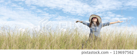Banner Portrait Asian Woman relaxing in green park. Happy Relax asian woman smiling face at outdoors garden. Women enjoy nature freedom lifestyle. Greenery wellbeing outside in nature with copy space 119697562
