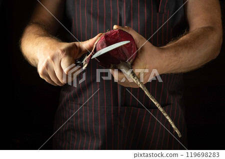 The cook peels red beets with a knife before preparing a vegetable dish for dinner. The concept of preparing a vegetable diet in a restaurant kitchen 119698283