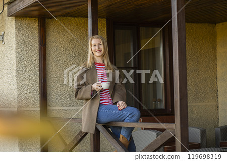 relax and enjoying quiet autumn moment on balcony with coffee, outdoor furniture, calm woman relax and enjoying quiet autumn moment on balcony with coffee, outdoor furniture, calm woman 119698319