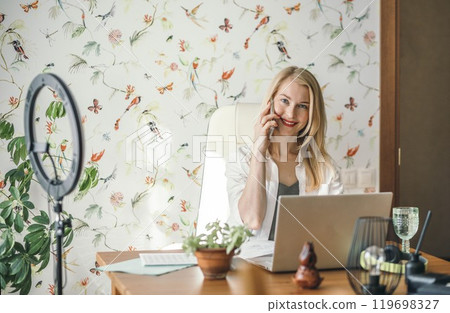remote worker staying connected with colleagues or clients through smartphone and laptop, woman in business 119698327