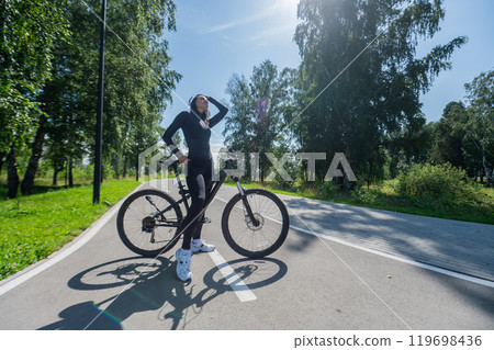 Caucasian woman riding a bike in a park.  119698436