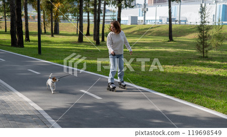 Caucasian woman roller skating with her jack russell terrier dog in park.  119698549