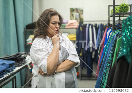 Caucasian fat woman chooses clothes. Plus size store.  119698682