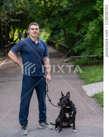 Caucasian man walking with a pitbull terrier dog. Vertical photo.  119698701