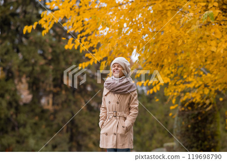 Caucasian girl in a beige coat and beret walks in the park in autumn. Caucasian girl in a beige coat and beret walks in the park in autumn. 119698790