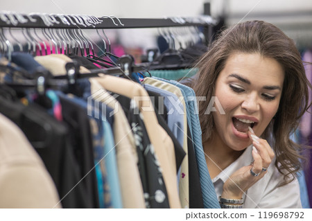A fat woman chooses clothes in a plus size store.  119698792