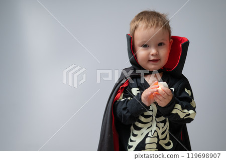 Little Caucasian boy in Dracula costume holding candle on white background. Little Caucasian boy in Dracula costume holding candle on white background. 119698907