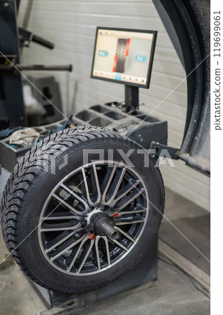 Mechanic balancing a wheel in a workshop.  119699061