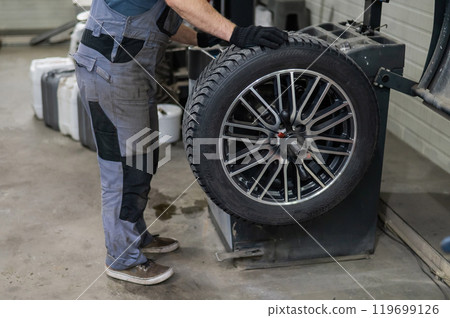 Mechanic balancing a wheel in a workshop.  119699126