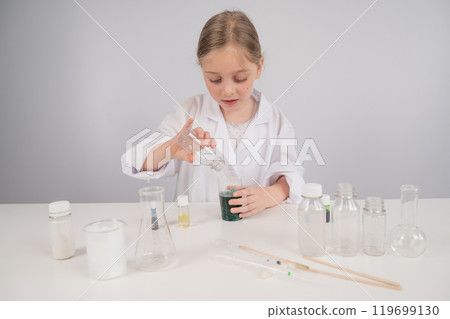 Caucasian girl doing chemical experiments on a white background. Caucasian girl doing chemical experiments on a white background. 119699130