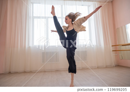 Caucasian woman dances contemporary in ballet class. Dancer in a jump. Caucasian woman dances contemporary in ballet class. Dancer in a jump. 119699205