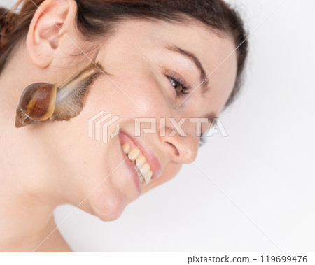 A beautiful caucasian woman is lying and snails are crawling over her face. Skin care and anti-aging 119699476
